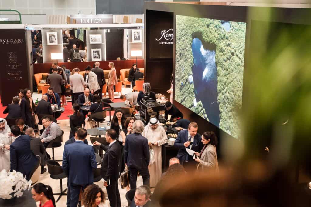 Crowd of people at a photography exhibition with large screen display.