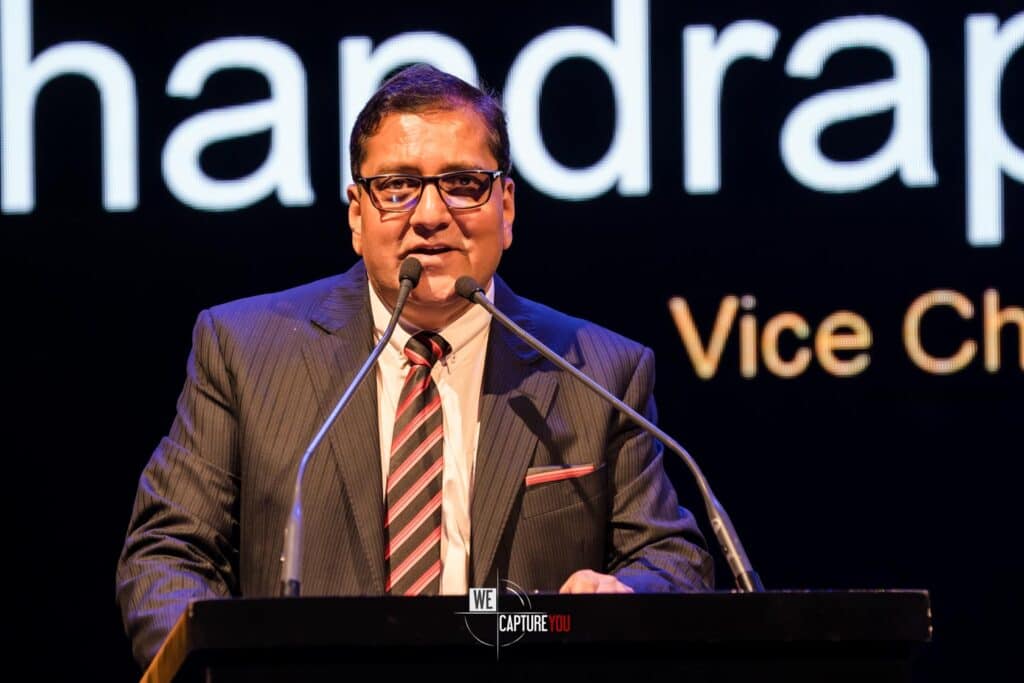 Business speaker at a corporate event in Dubai with a microphone and presentation background.