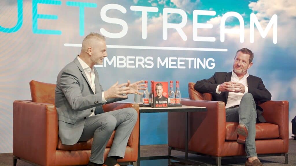 Two men in suits having a discussion on stage at JETSTREAM Dubai event.