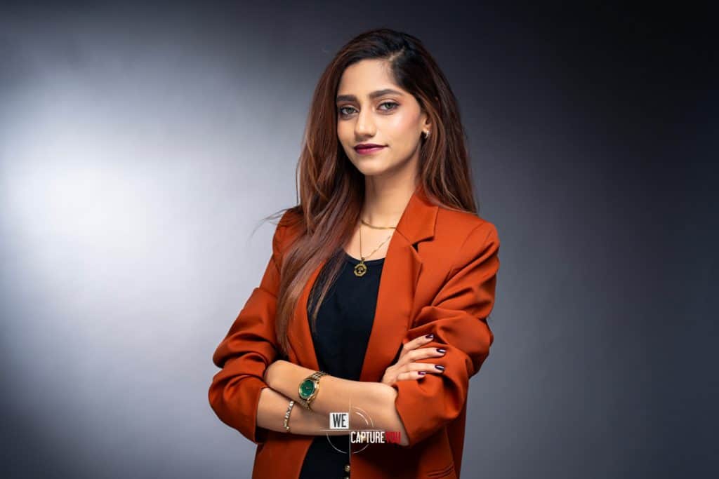 Confident young woman in a rust-colored blazer and black top posing for professional photo.