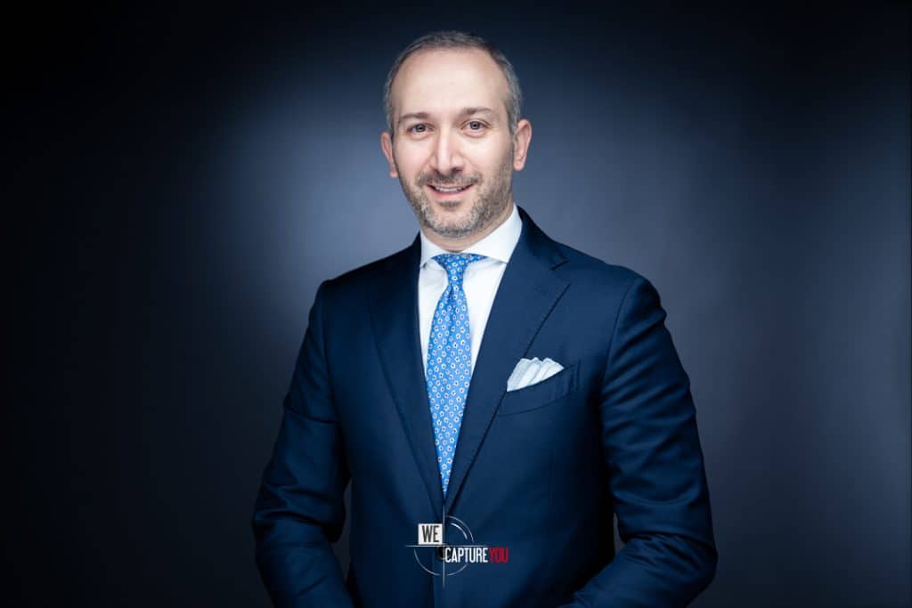 Professional businessman in a navy suit smiling for a corporate portrait.