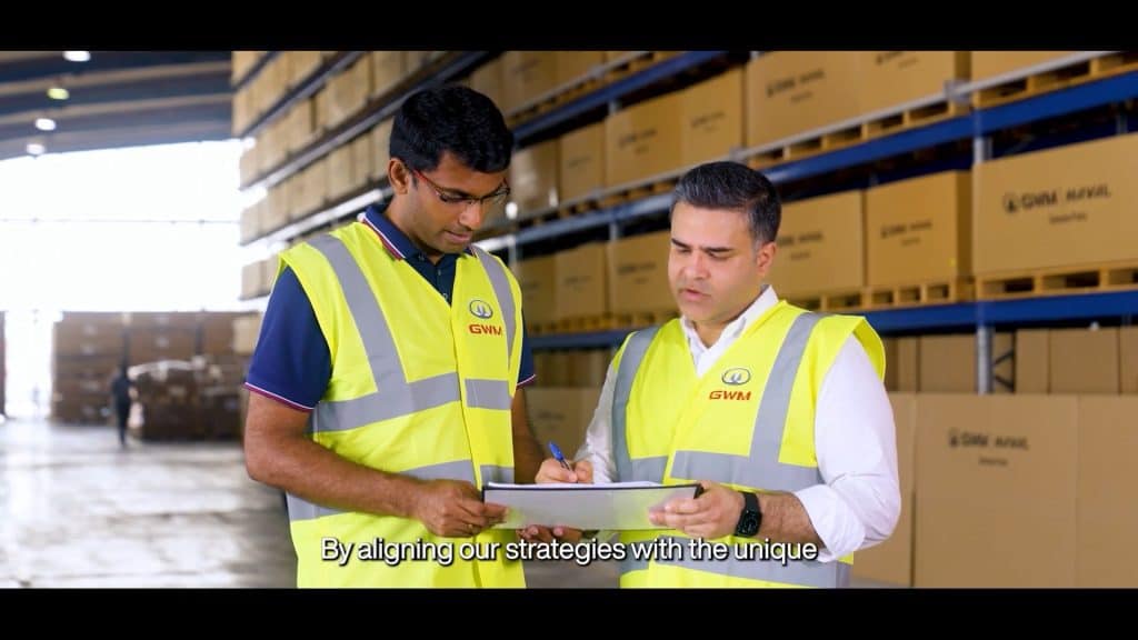 Two workers in safety vests discussing logistics at GWM Parts Distribution Centre.