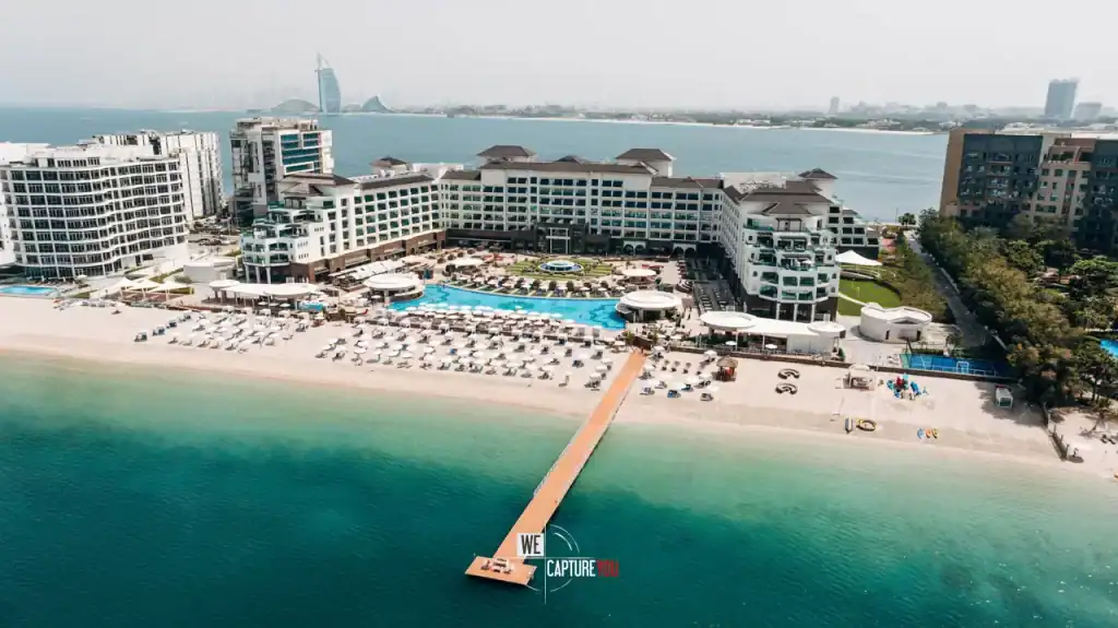 Aerial view of a luxury beachfront resort with pool and beach in Dubai.