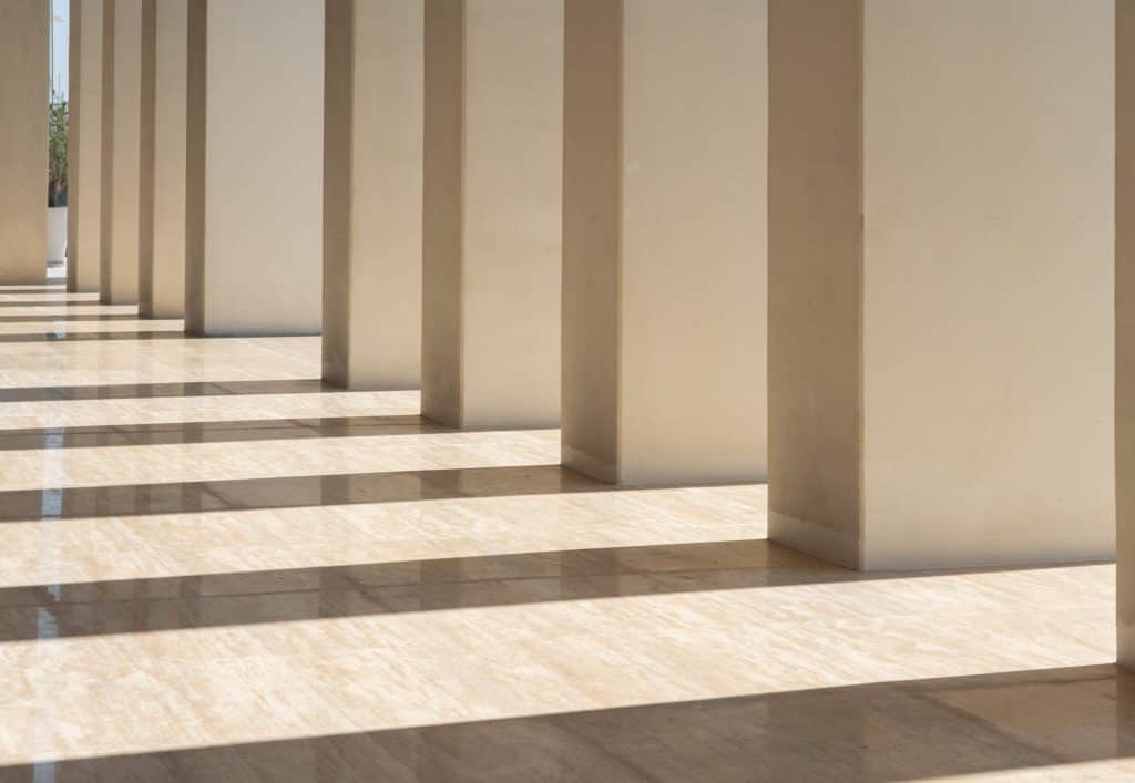Architectural columns casting shadows on a tiled floor.