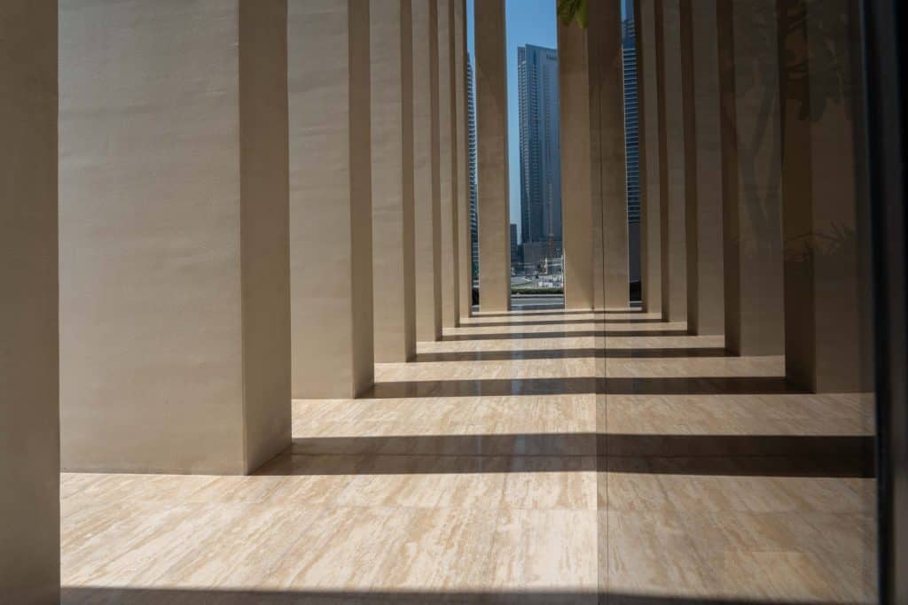 Contemporary corridor with tall columns and city skyline in background.