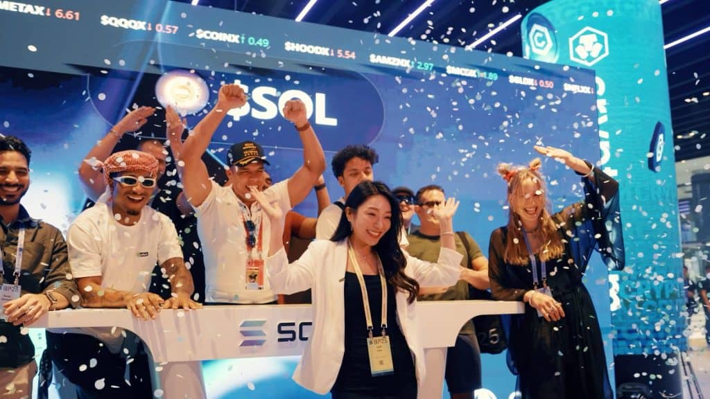 Group of diverse people celebrating at Solana Breakpoint event with confetti and stage backdrop.