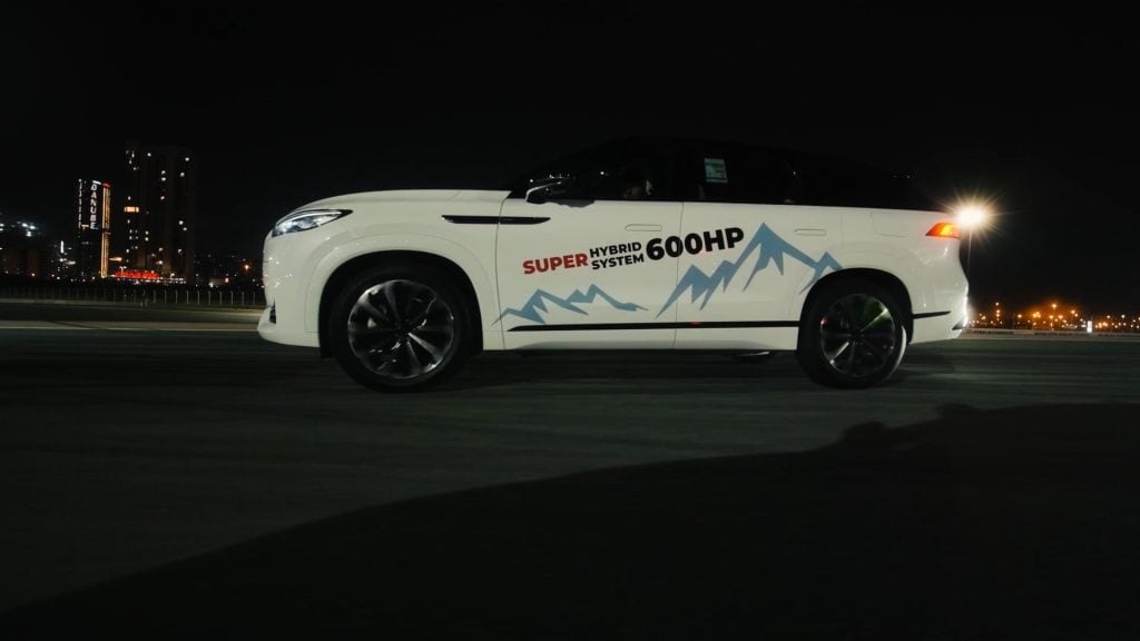 White hybrid SUV with mountain graphics at night, 600HP badge visible.